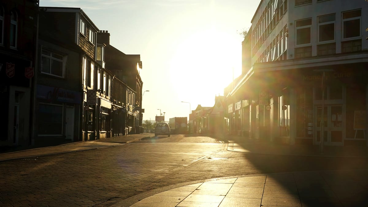 Low morning sun shining down a quiet, empty town street